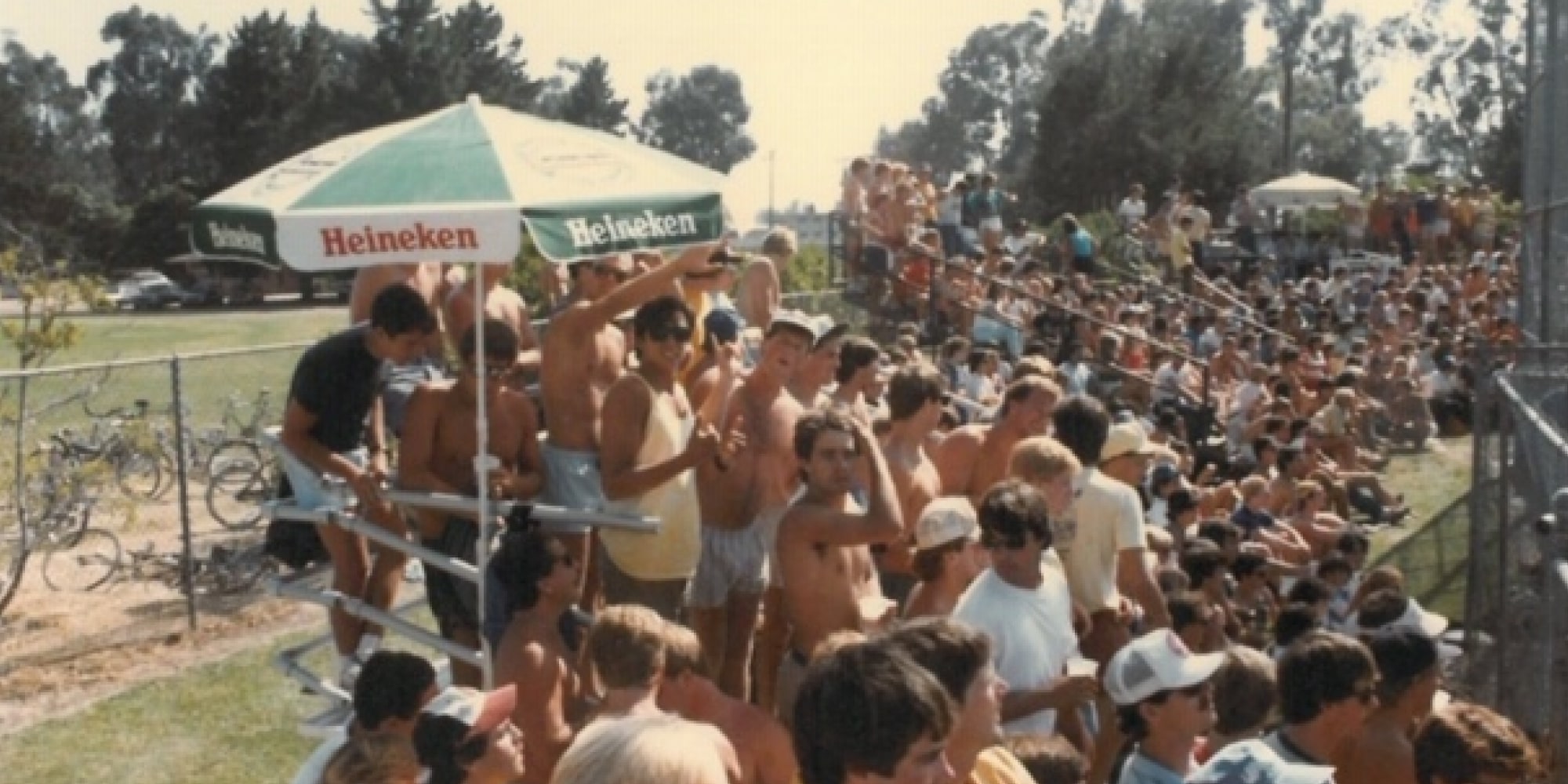 Older photo of fans at baseball game under umbrella