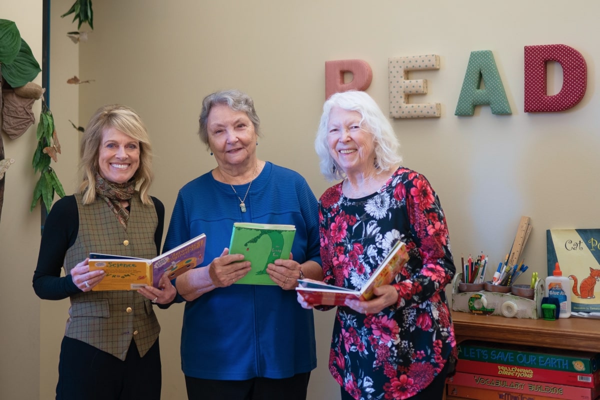 Emerita Carol Dixon, Ann Kaganoff ’75,’81 and Tina Hansen McEnroe ’89 holding books