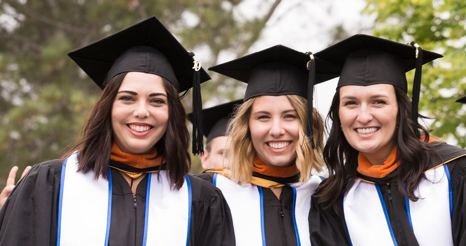 Three students wearing graduate outfits